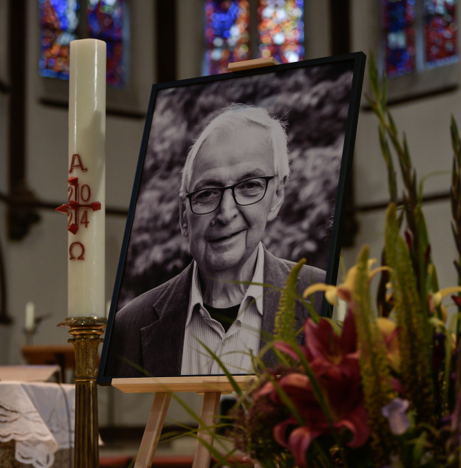 S/W-Foto von Klaus Töpfer auf einer Staffelei in der Kirche bei der Trauerfeier der Unionsfraktion. Daneben stehen eine Kerze und Blumen.