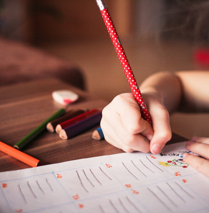 Kinderhand hält Stift und schreibt in Heft