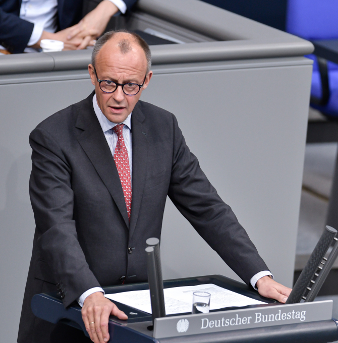 Friedrich Merz im Deutschen Bundestag. Er steht am Rednerpult mit der Aufschrift Deutscher Bundestag und hält eine Rede.